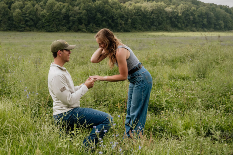 Man kneeling in a field of wildflowers to recreate his wedding proposal.