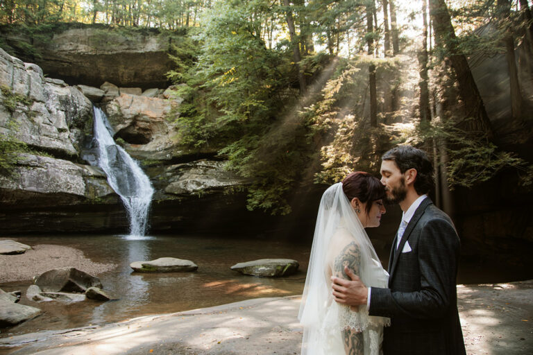 Couple sharing their first kiss as husband and wife with Cedar Falls in the background.