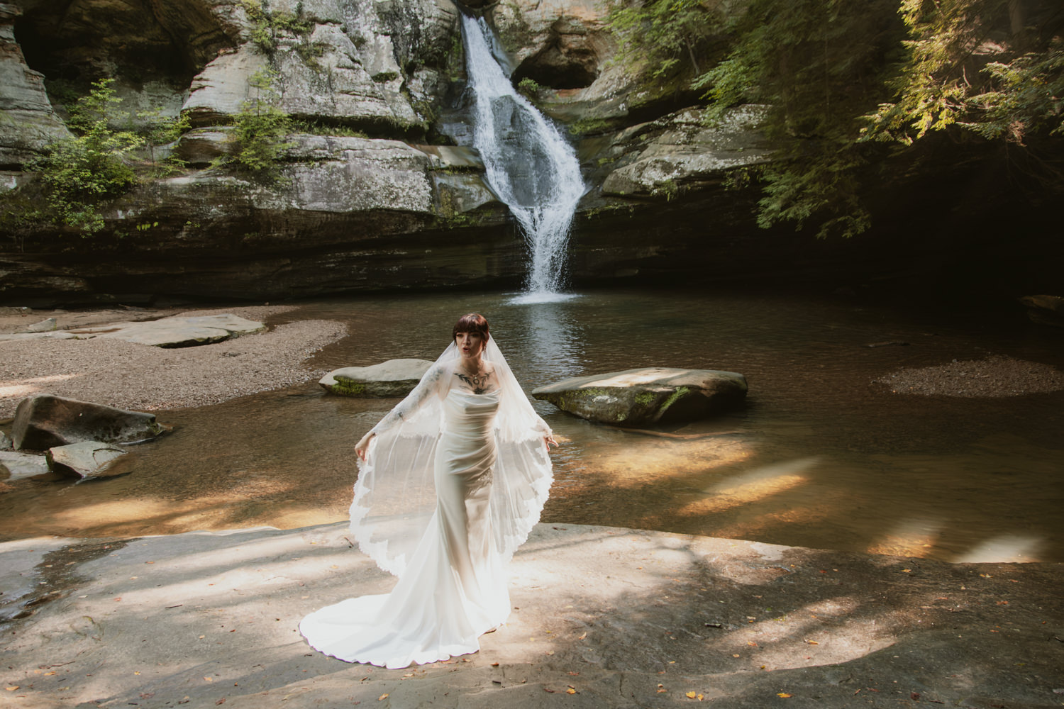 Rushing waters of Cedar Falls cascading into a natural pool surrounded by high sandstone walls.