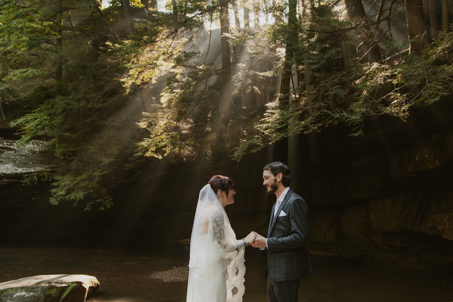 Couple whispering private vows to each other standing near the edge of the creekbed.