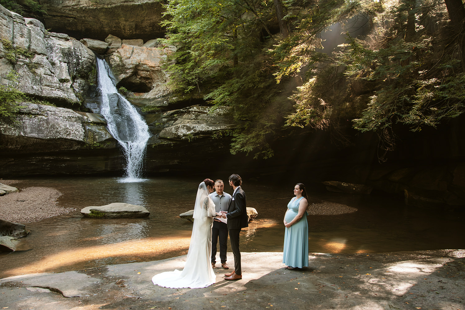 Close friend officiating a wedding ceremony for a couple in front of a towering rock face.
