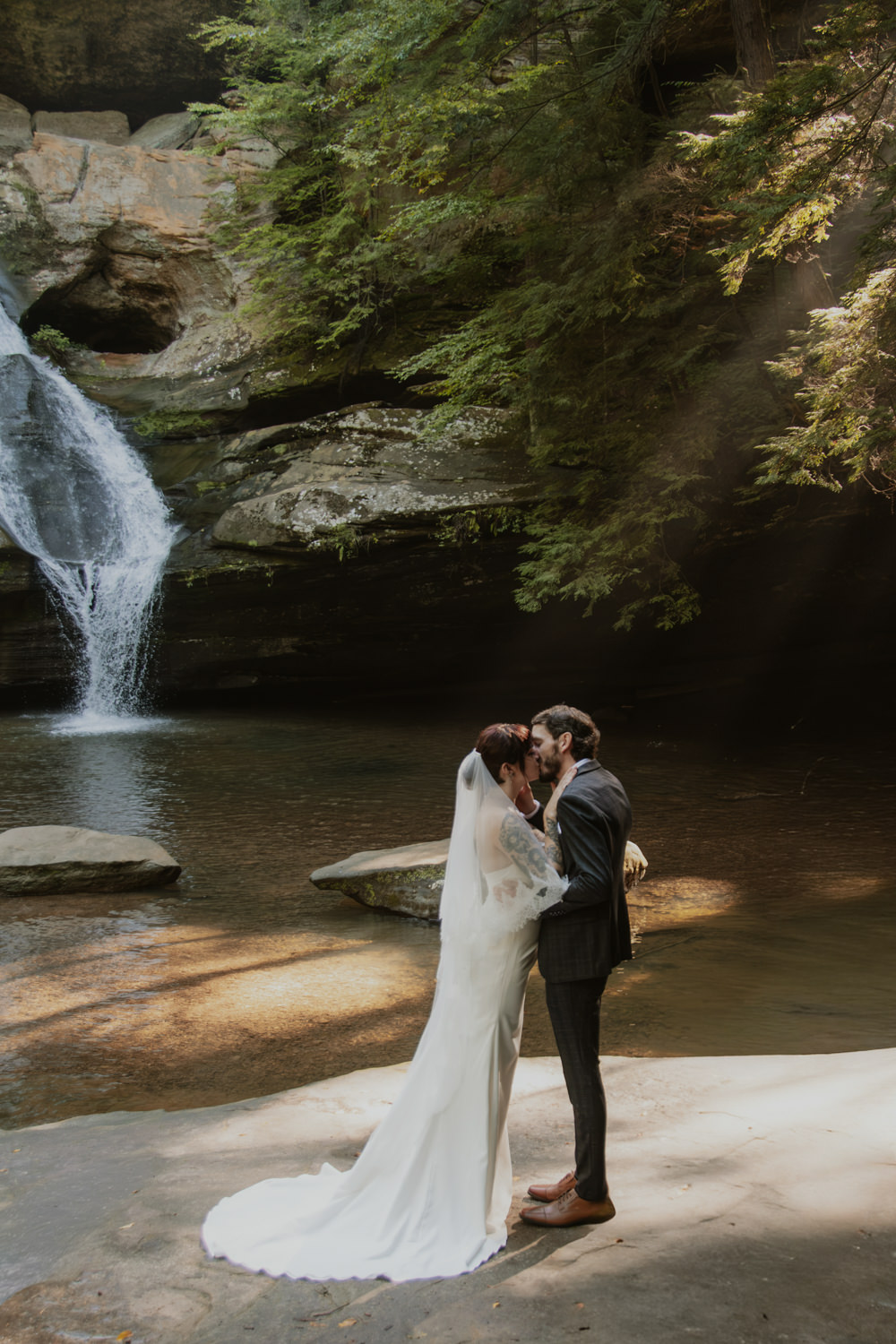 Couple sharing their first kiss as husband and wife with Cedar Falls in the background.