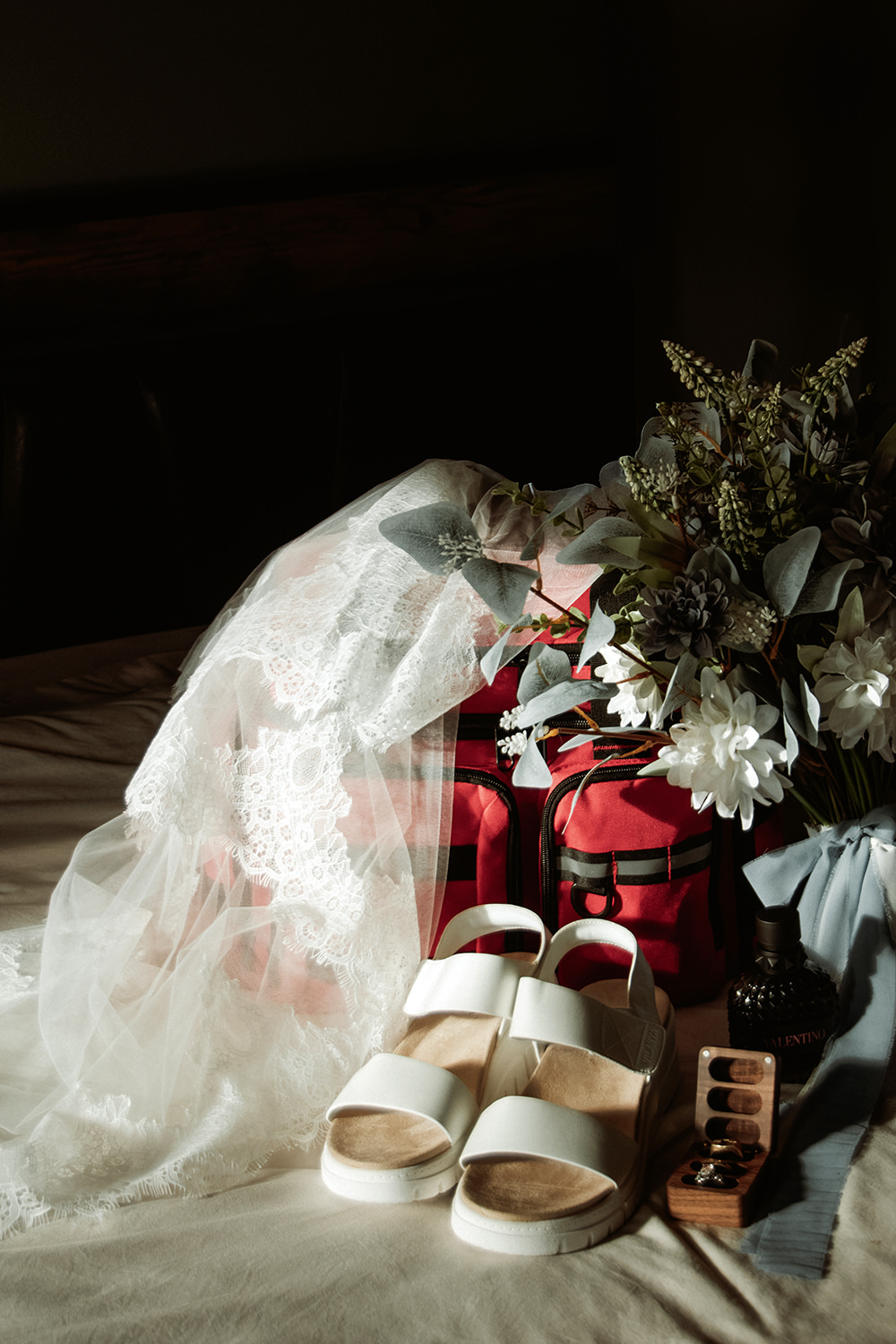 Detail shot of bridal jewelry, wedding rings, and medical scissors arranged on a wooden surface.
