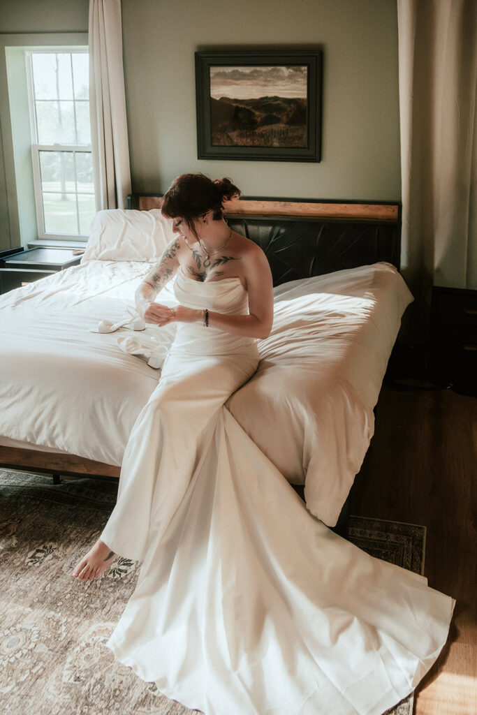 Bride sitting on a bed in her wedding dress, getting ready for the ceremony.