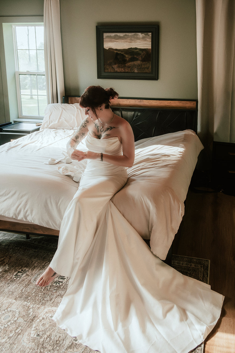 Bride sitting on a bed in her wedding dress, getting ready for the ceremony.