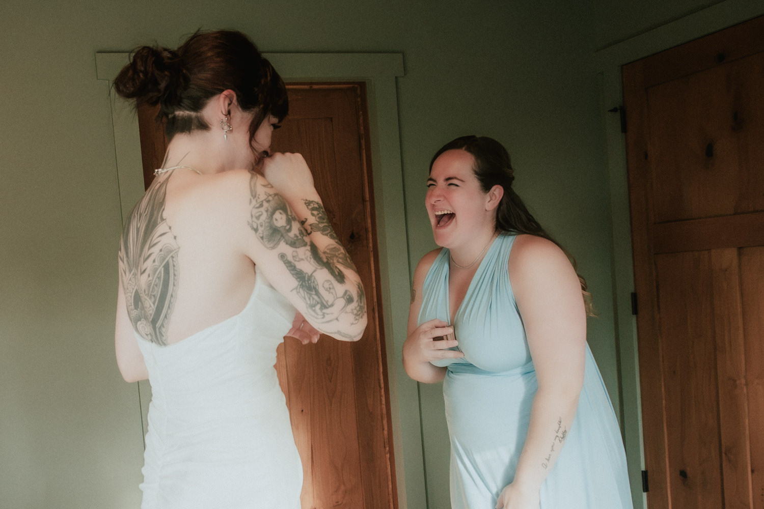 Bride and bridesmaid sharing a laugh while getting ready.