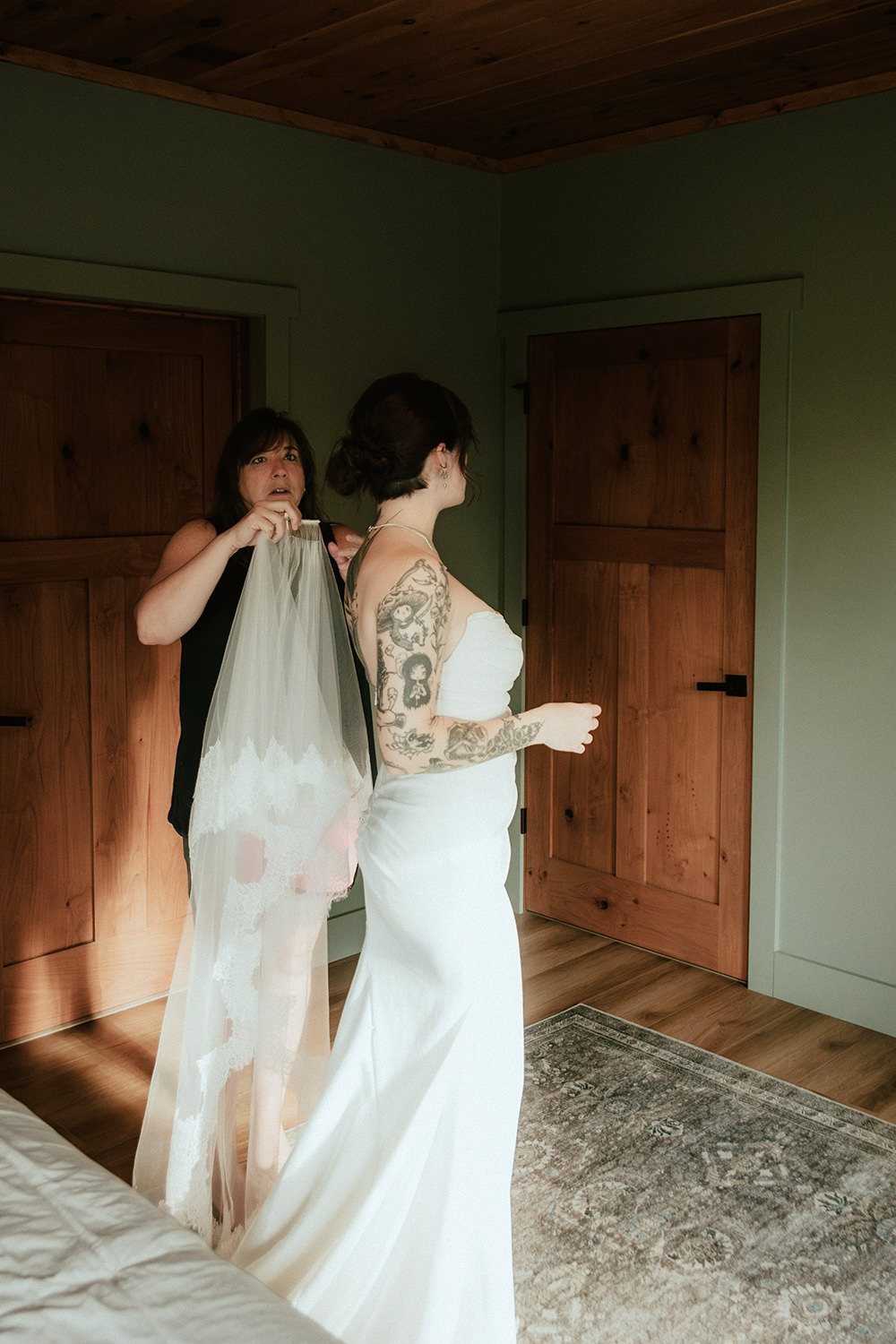 A mother of the bride holds the veil while the bride gets ready.