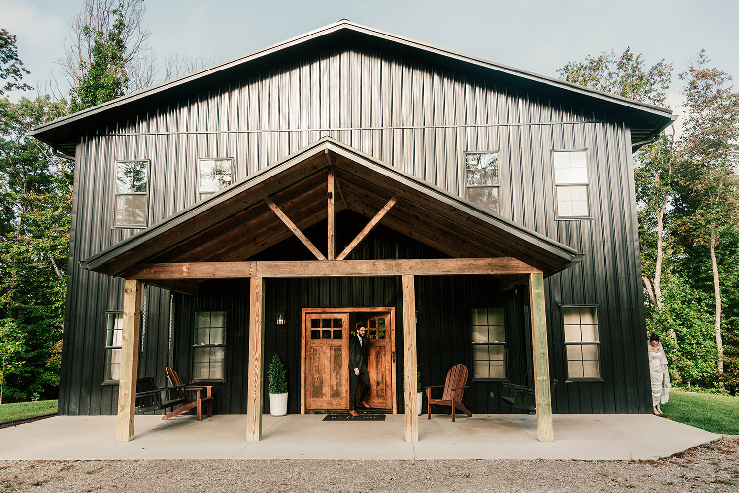 A groom exits the lodge through the front door while a bride peeks around the corner during their first look.