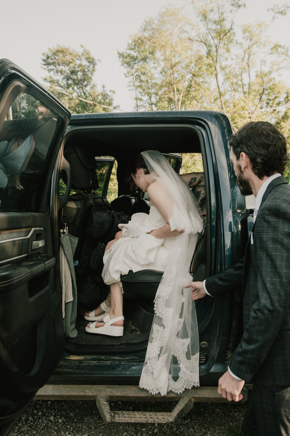 Groom helps bride get in a black truck to head to a Cedar Falls ceremony.