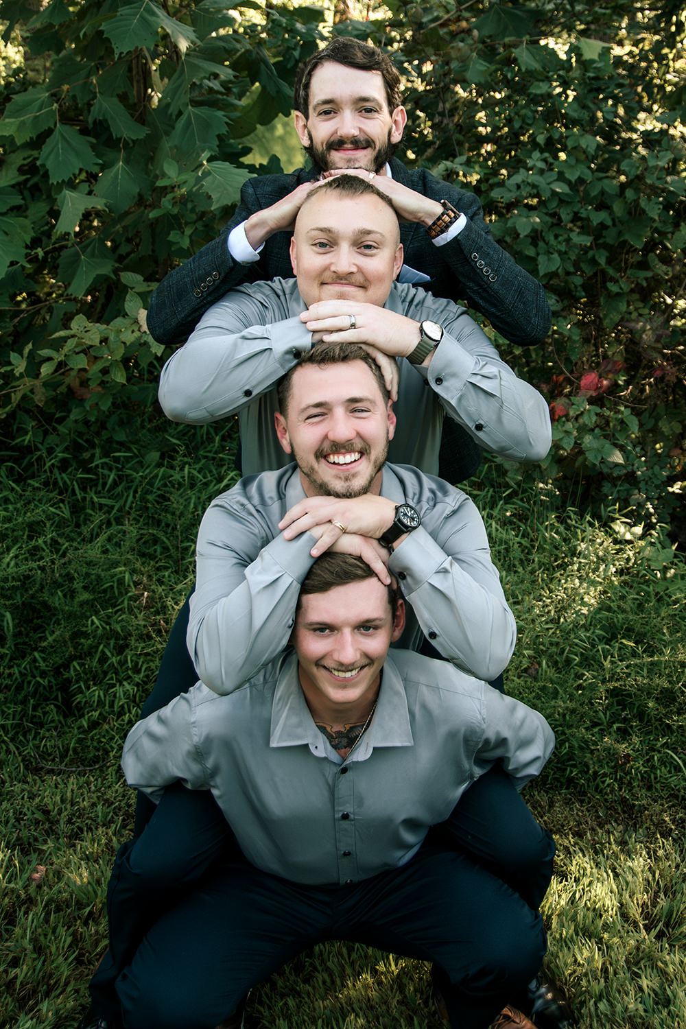 Groom posing for a fun group photo with their family and friends outside the cabin.