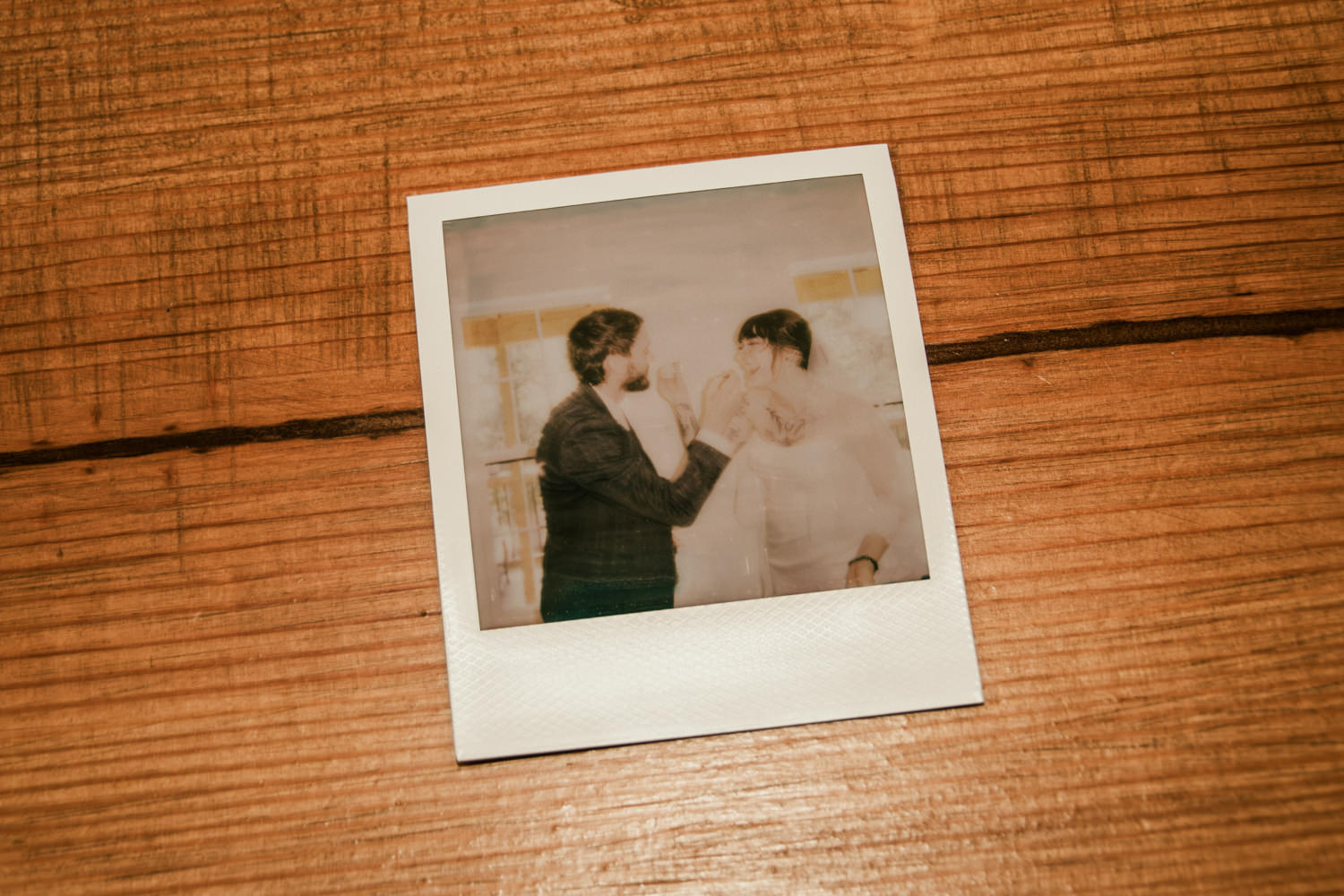 Polaroid of a couple eating wedding cake.