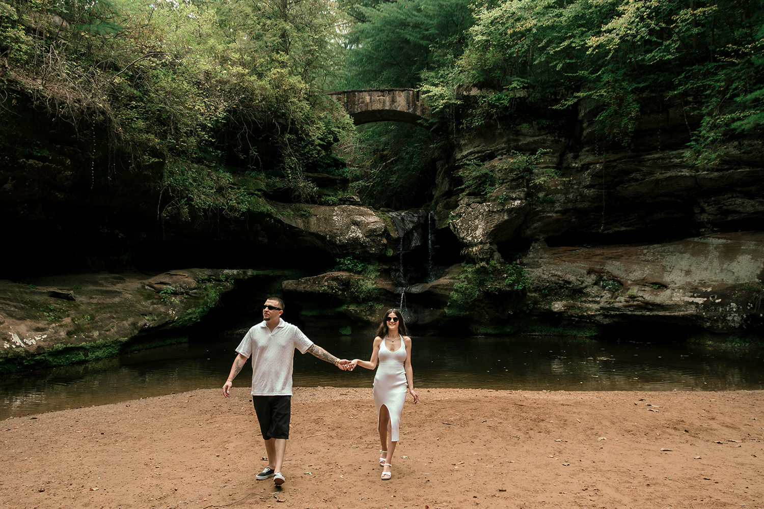 A couple holds hands in front of a waterfall at Old Man's Cave.
