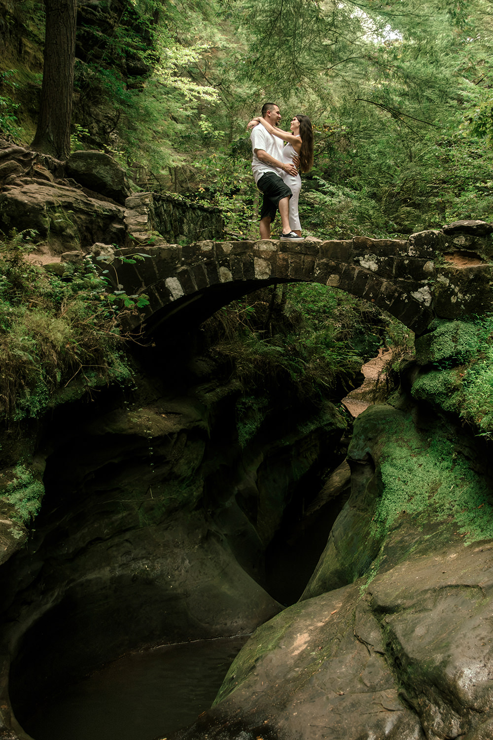 A couple holds hands while walking across the upper stone bridge at Old Man’s Cave in Hocking Hills.