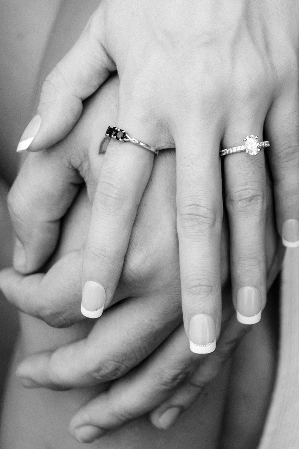 Black and white photo of a couples hands with an engagement ring.
