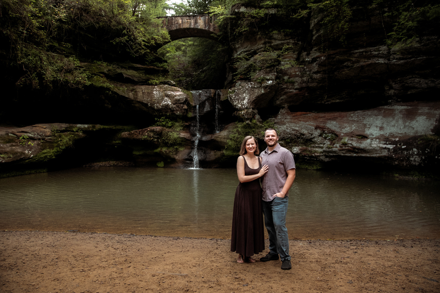 Close-up of a married couple smiling and embracing near the mossy sandstone cliffs at Upper Falls.