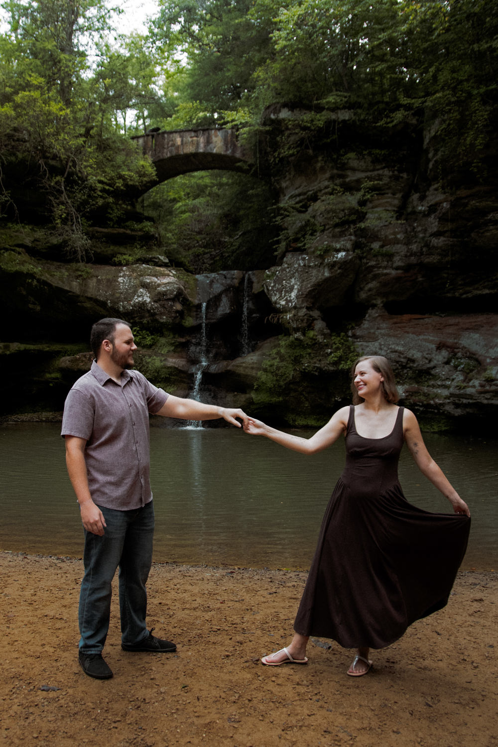 Full-length shot of a couple standing near Upper Falls in Hocking Hills.