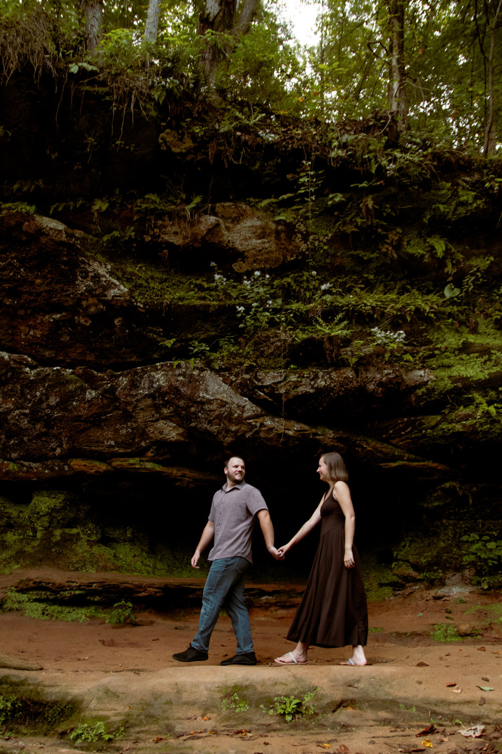 Couple sitting side by side on a large fallen log in a secluded woodland hollow.