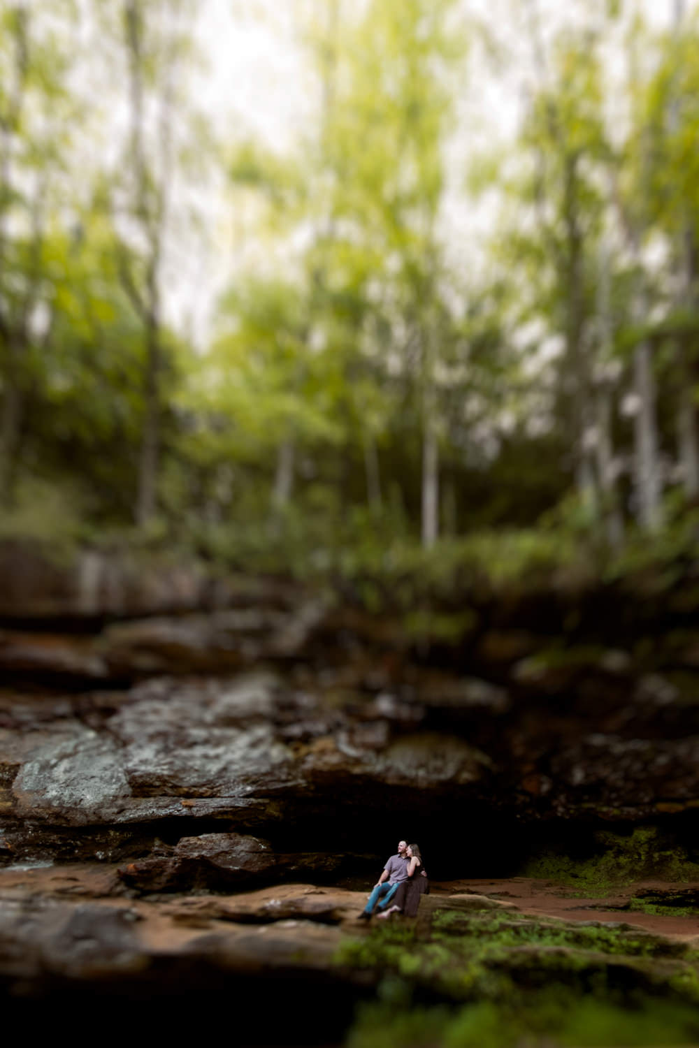 Wide artistic portrait of a couple sitting on a cliffside overlook in Hocking Hills.