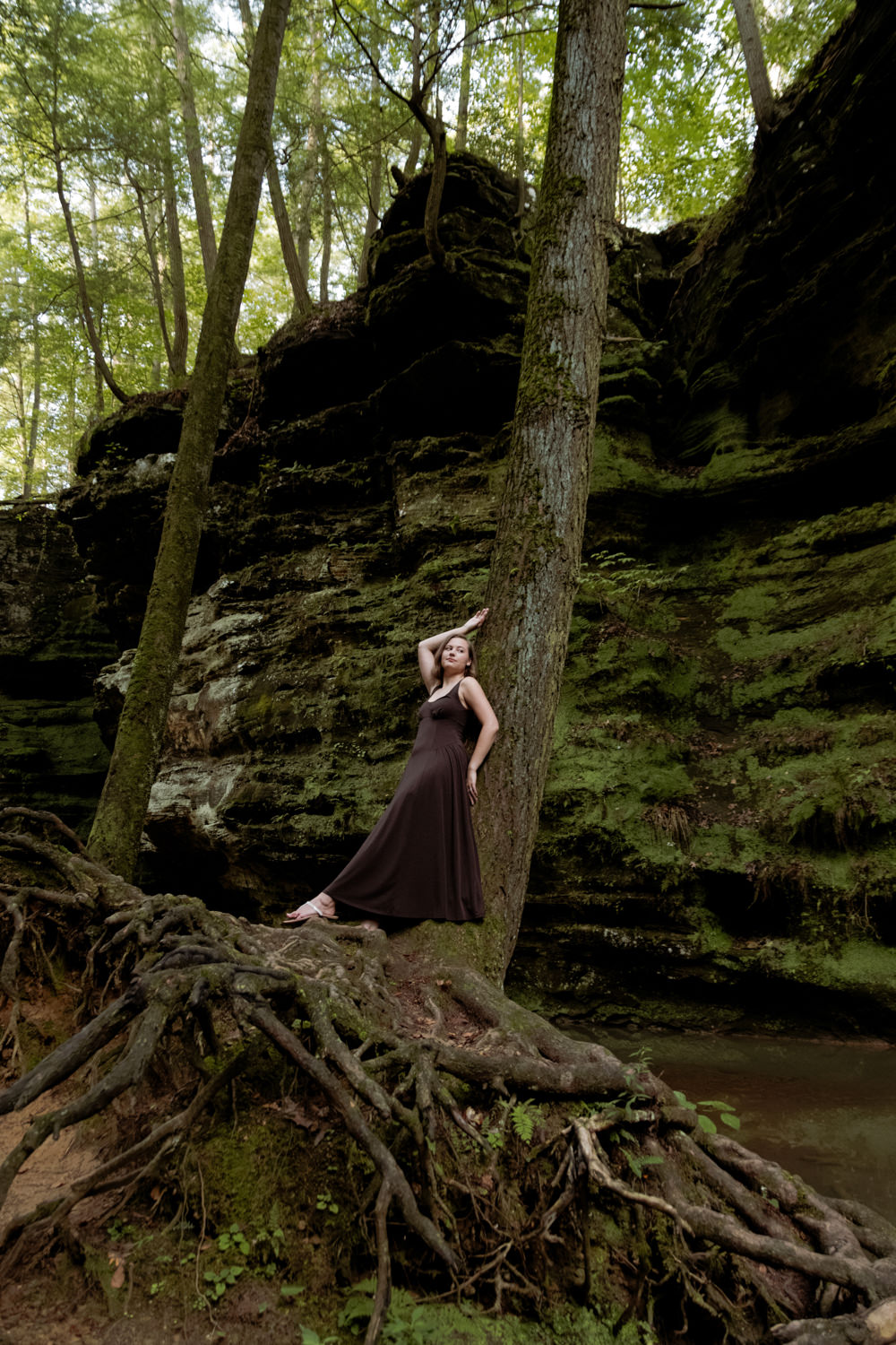 Wide scenic portrait of a woman standing on tree roots in Hocking Hills.