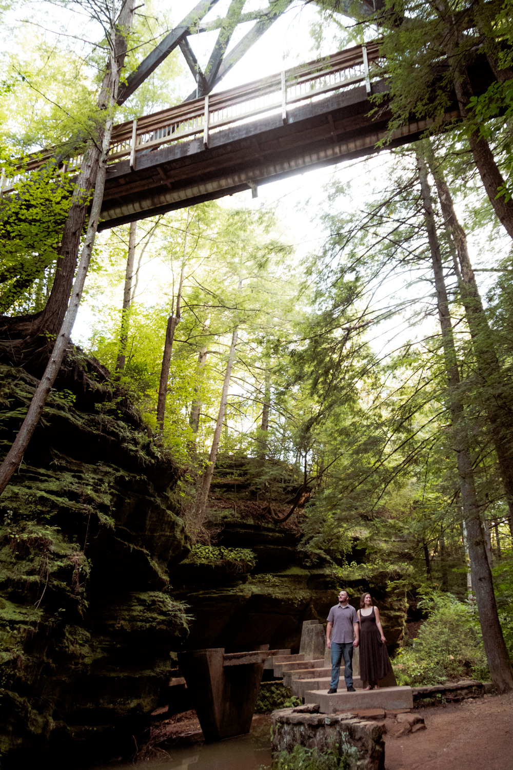 Couple walking together along the stone steps descending into the deep Hocking Hills gorge under the A-frame bridge.