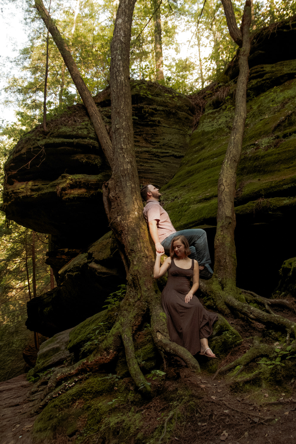Couple sharing a quiet moment on a rock ledge surrounded by vibrant green ferns and gorge hemlocks.